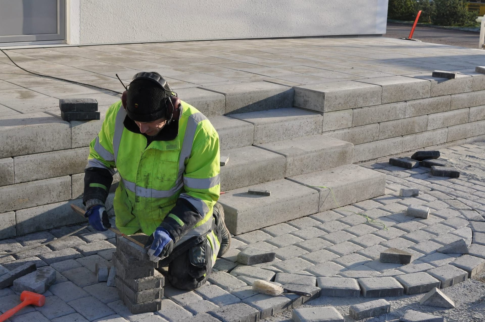 Arbetare mäter stenar till cirkelmönster på lägre patio